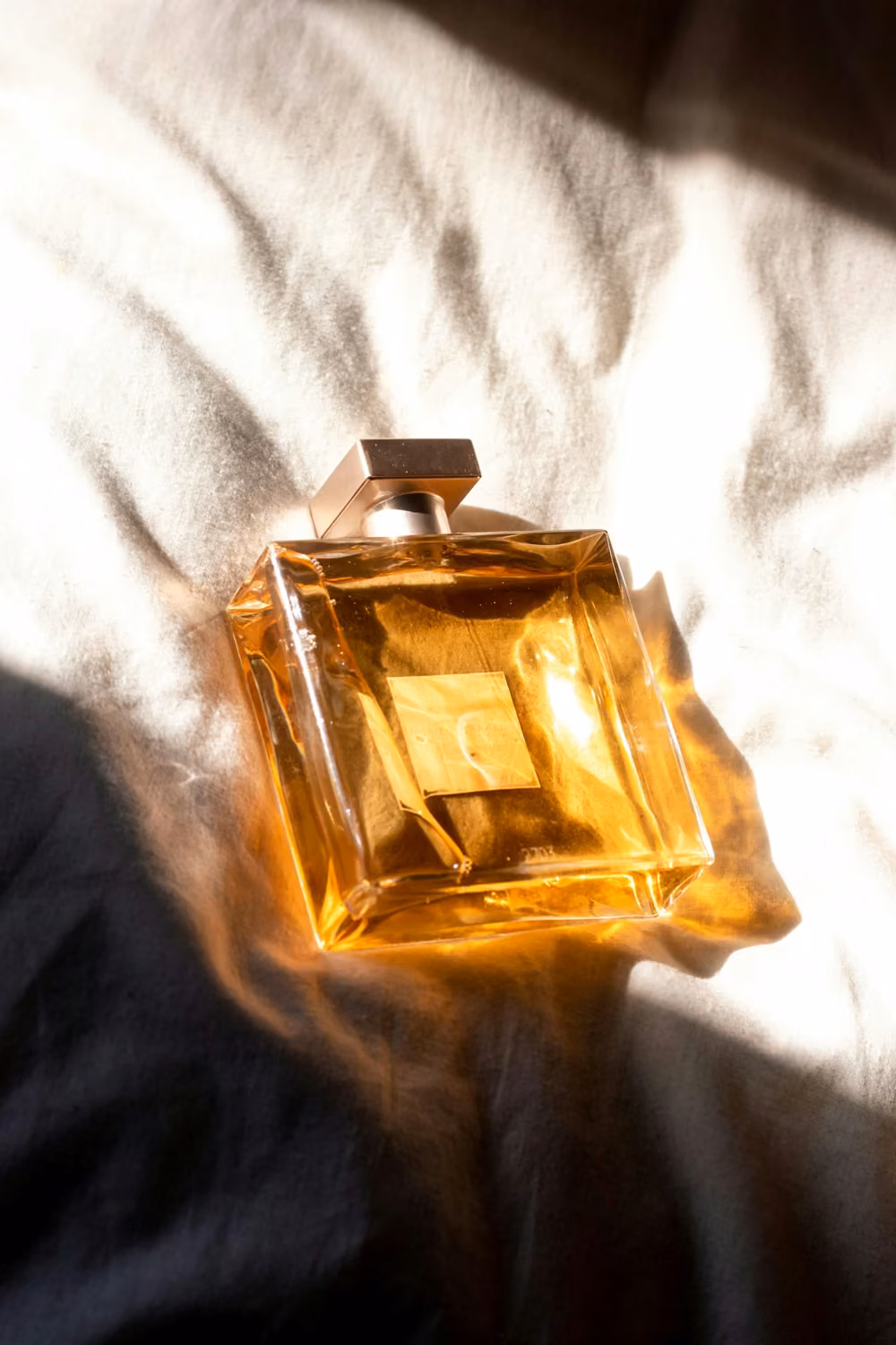 Gold perfume bottle on white textile