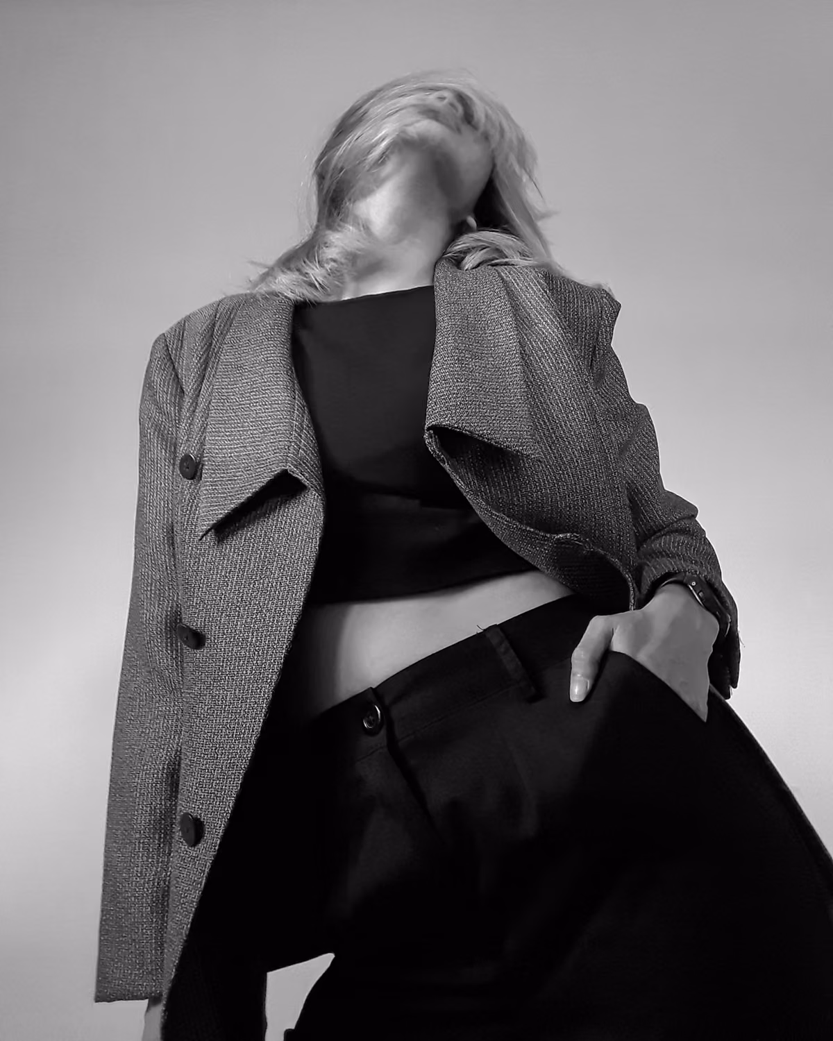 A person in a blazer and trousers with a hand in a pocket