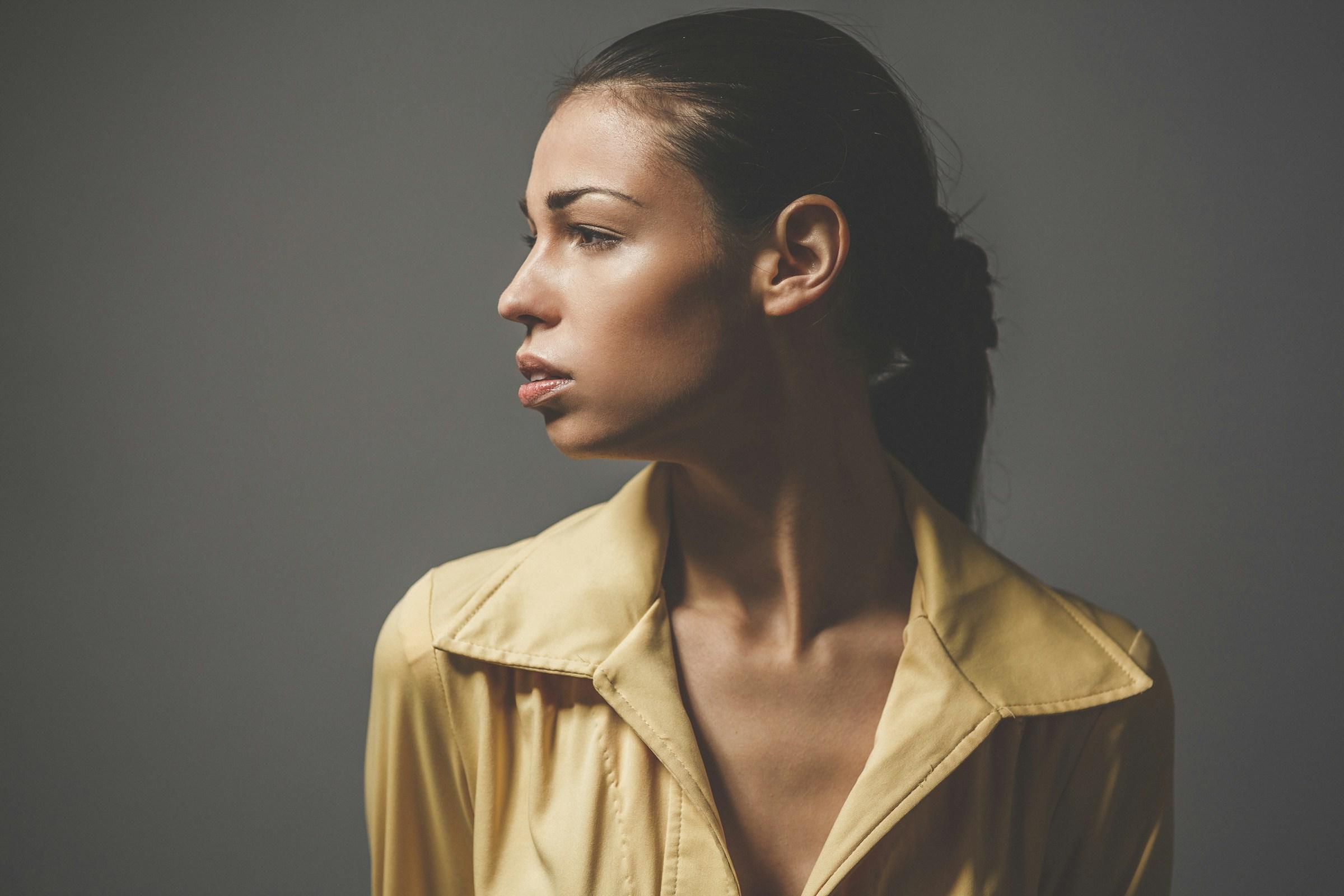 Studio portrait of a woman in a camel shirt, looking to one side