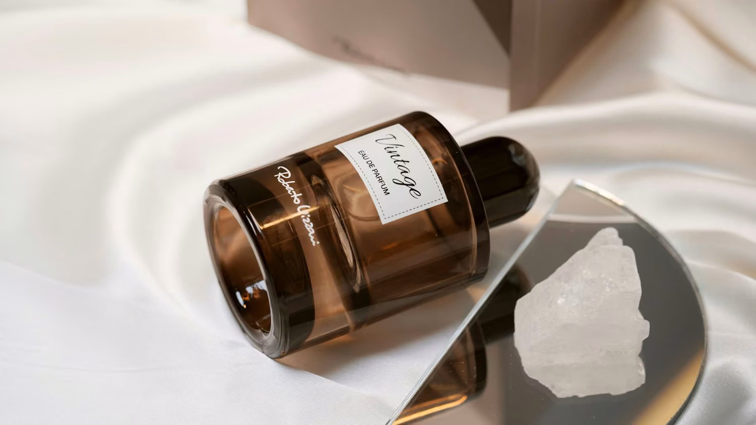 A brown glass perfume bottle on white satin