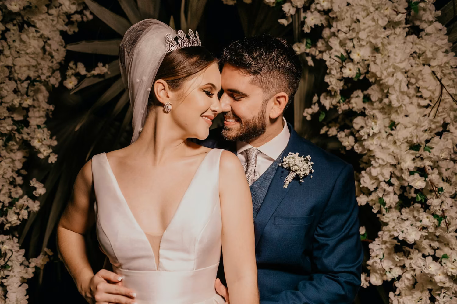 Man in blue suit kissing woman in white sleeveless dress