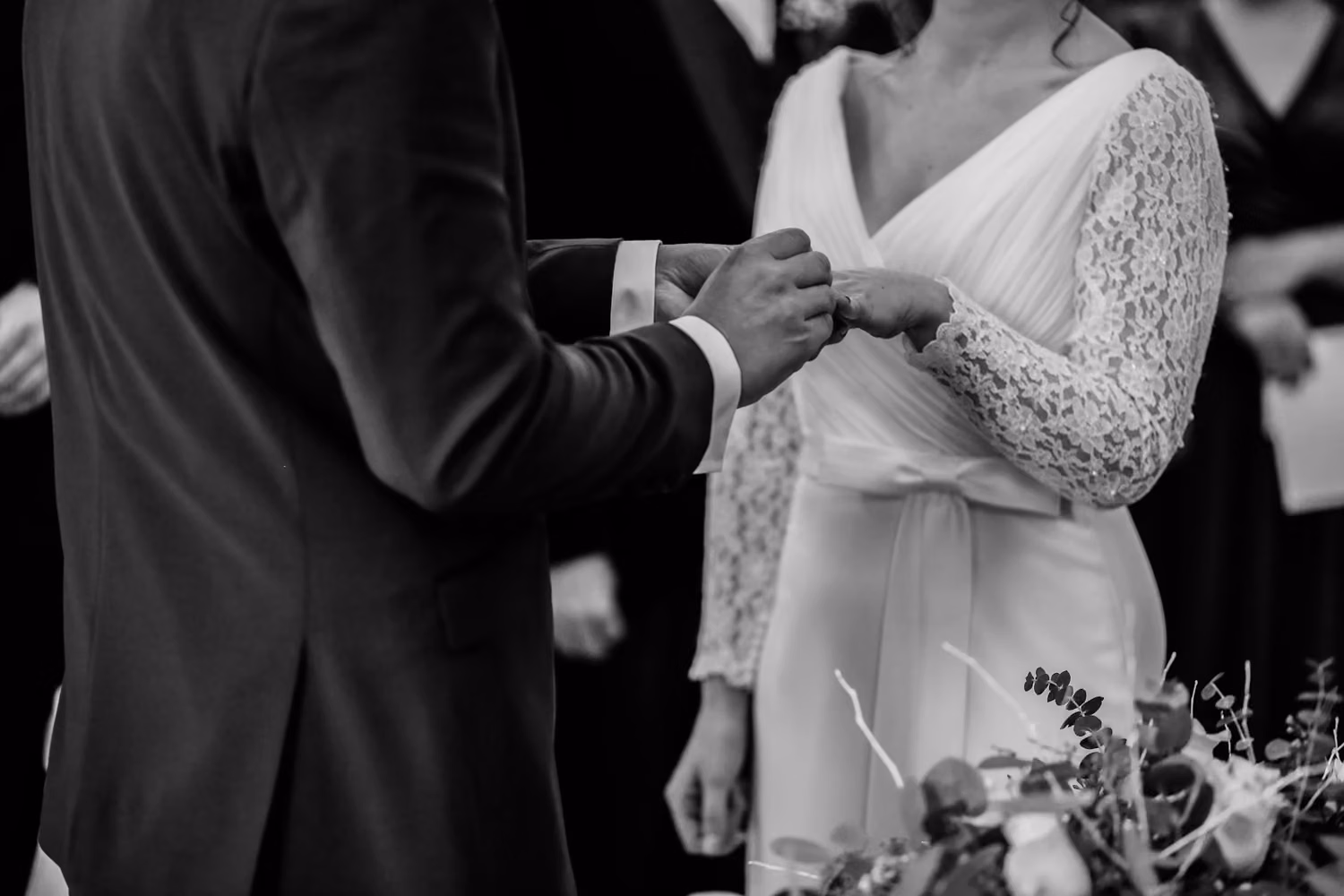 Grayscale photo of man insert ring into woman during wedding ceremony